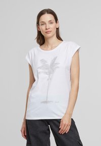 T-shirt en coton blanc à manches courtes, avec un graphique de palmier gris clair et une coupe ample. Texture lisse et design décontracté.