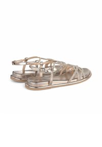 Metalen gouden sandalen met gevlochten banden, verstelbare enkelgesp en platte zolen. Gladde textuur met glinsterende accenten.