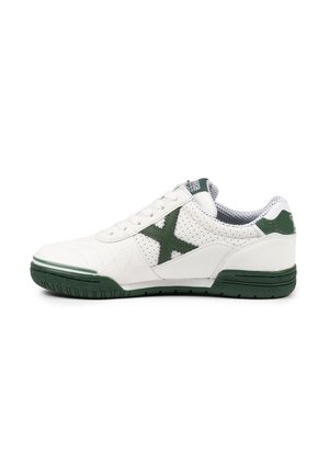 Zapatilla blanca de caña baja con suela, talón y logo lateral "X" en verde oscuro, con detalles de cuero perforado y acolchado.