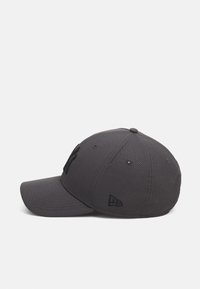 Gorra de béisbol gris con una tela texturizada, visera curva, logo negro al frente y un logo bordado en el lado.