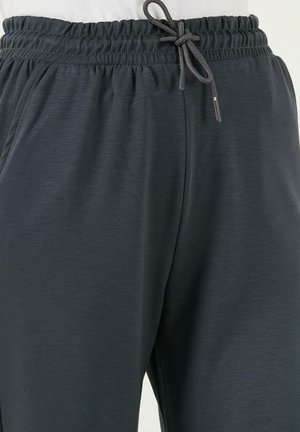 Pantalones deportivos gris oscuro hechos de una tela suave y texturizada. Cuentan con una cinturilla elástica con cordón ajustable para un ajuste personalizable.