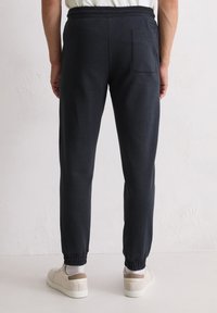 Marineblaue Jogginghose mit elastischem Bund, zulaufenden Beinen und elastischen Bündchen. Mit einer Gesäßtasche und glattem, weichem Stoff.