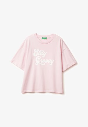 Růžové bavlněné tričko s krátkým rukávem, s textem "Stay Groovy" v bílých zaoblených písmenech napříč přední částí. Hladká textura, uvolněný střih.