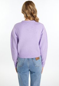 Fialový pletený svetr s volným střihem, spadlými ramenními švy a žebrovaným lemem. V kombinaci se světle modrými džíny s vysokým pasem.