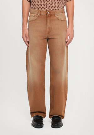 Brune denimjeans med løs passform, med klassisk knapp- og glidelåslukking, og fem lommer, kombinert med svarte sko.