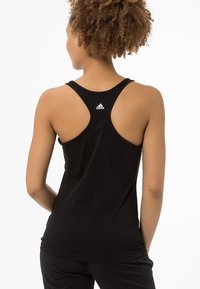 Czarny sportowy top na ramiączkach typu racerback, wykonany z lekkiego materiału, z małym białym logo na plecach.