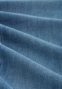 Heledad on heled sinine, millel on peen tekstuur ja mis näitab mitmeid voldikesi ning klassikalist kootud mustrit, mis on tüüpiline teksakangastele.