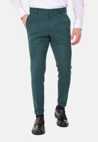 Pantaloni teal con una vestibilità sartoriale, dotati di tasche frontali, design slim fit e risvolto alla caviglia, abbinati a scarpe nere lucide.