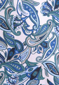 Een stof met een paisley-patroon met meerdere tinten blauw en groen, omlijnd met beige, op een lichte achtergrond. Gestructureerde afwerking.