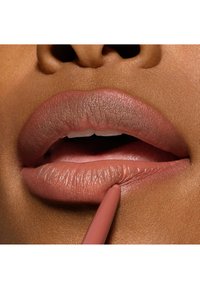 Matita per labbra nude applicata su labbra piene; le labbra hanno una finitura semi-matte con contorni ben definiti; texture liscia e colore rosa-marrone chiaro.