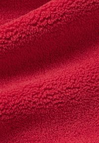 Tissu en polaire rouge avec une surface douce et texturée, affichant une densité de poils uniforme et un aspect lisse et chaud.