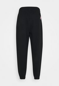 Black sweatpants with an elastic waistband, tapered cuffs, and a small logo on the back pocket. Soft fabric with a smooth texture.
