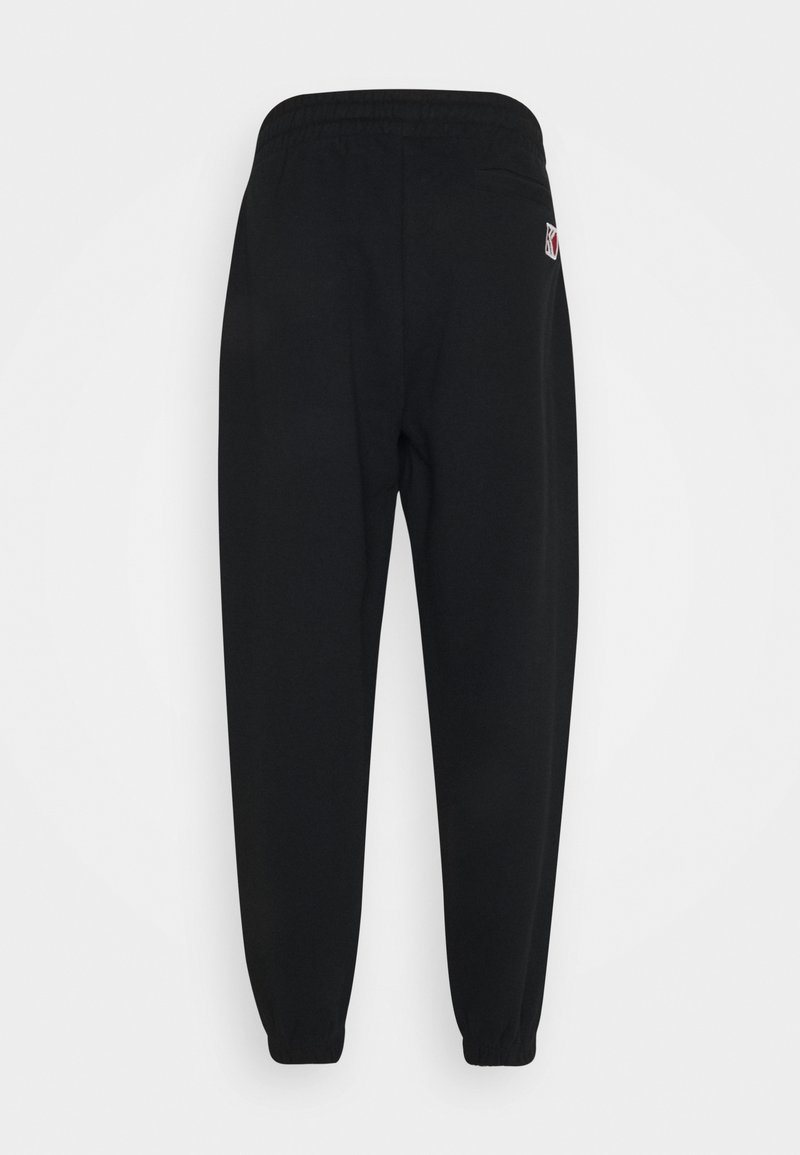 Black sweatpants with an elastic waistband, tapered cuffs, and a small logo on the back pocket. Soft fabric with a smooth texture.