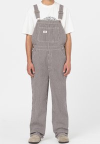 Salopette rayée en tissu de coton, équipée de bretelles ajustables, d'une poche poitrine et d'une coupe décontractée. Couleur : rayures grises et blanches.