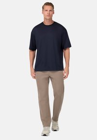 Marinblå kortärmad T-shirt med rund halsringning, i kombination med beige sweatpants. Mjuk kvalitet, avslappnad passform och sneakers i neutrala färger.