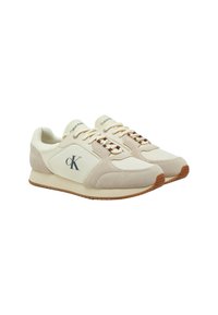 Sneakers Calvin Klein in beige, realizzati in materiali scamosciati e in pelle. Presentano una punta tonda, lacci bianchi e una suola in gomma texture. Dettaglio del logo evidente.