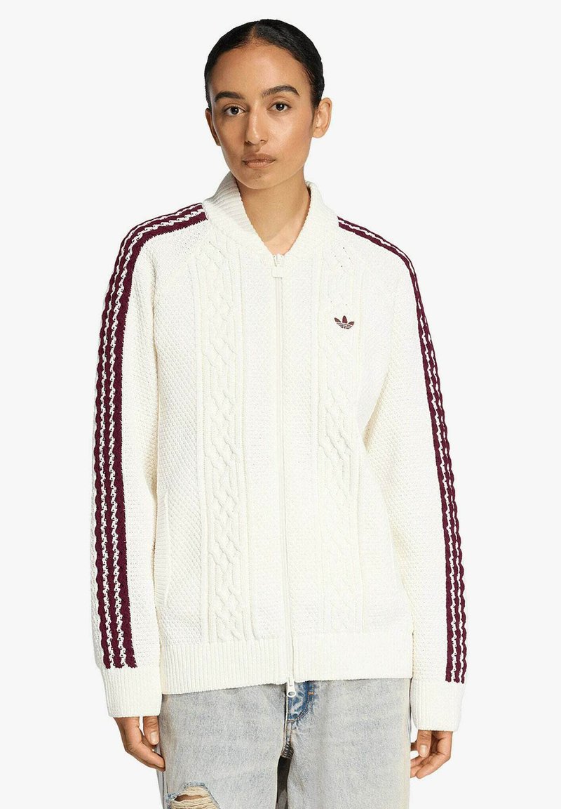 Maglione bianco lavorato a maglia con motivo a treccia, cerniera completa, polsini e orlo a coste. Presenta strisce bordeaux e logo sul petto a sinistra.