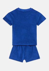 Conjunto de dos piezas de algodón rizado azul que incluye una camisa de manga corta y pantalones cortos. Textura suave con detalles acanalados en el escote y el dobladillo.