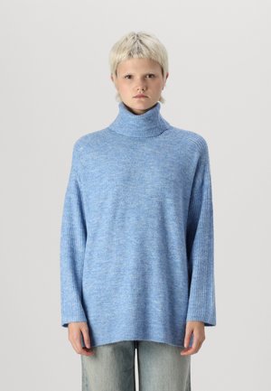 Light blue oversized turtleneck sweater in a soft, textured knit with ribbed accents on the collar and cuffs. Long sleeves, relaxed fit.