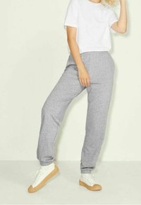 Grå bomullssvettsbyxor med elastiska muddar, kombinerat med en vit t-shirt och vita sneakers med en gummisula.