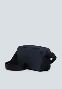 Borsa rettangolare blu navy con una texture liscia, dotata di una tracolla nera regolabile e logo in rilievo sul fronte. Chiusura con zip superiore.