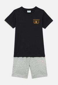 Μαύρο βαμβακερό T-shirt με κίτρινο λογότυπο "Champion" και γκρι σορτς από μαλακό ύφασμα. Τα σορτς διαθέτουν μικρό λογότυπο στο αριστερό πόδι.