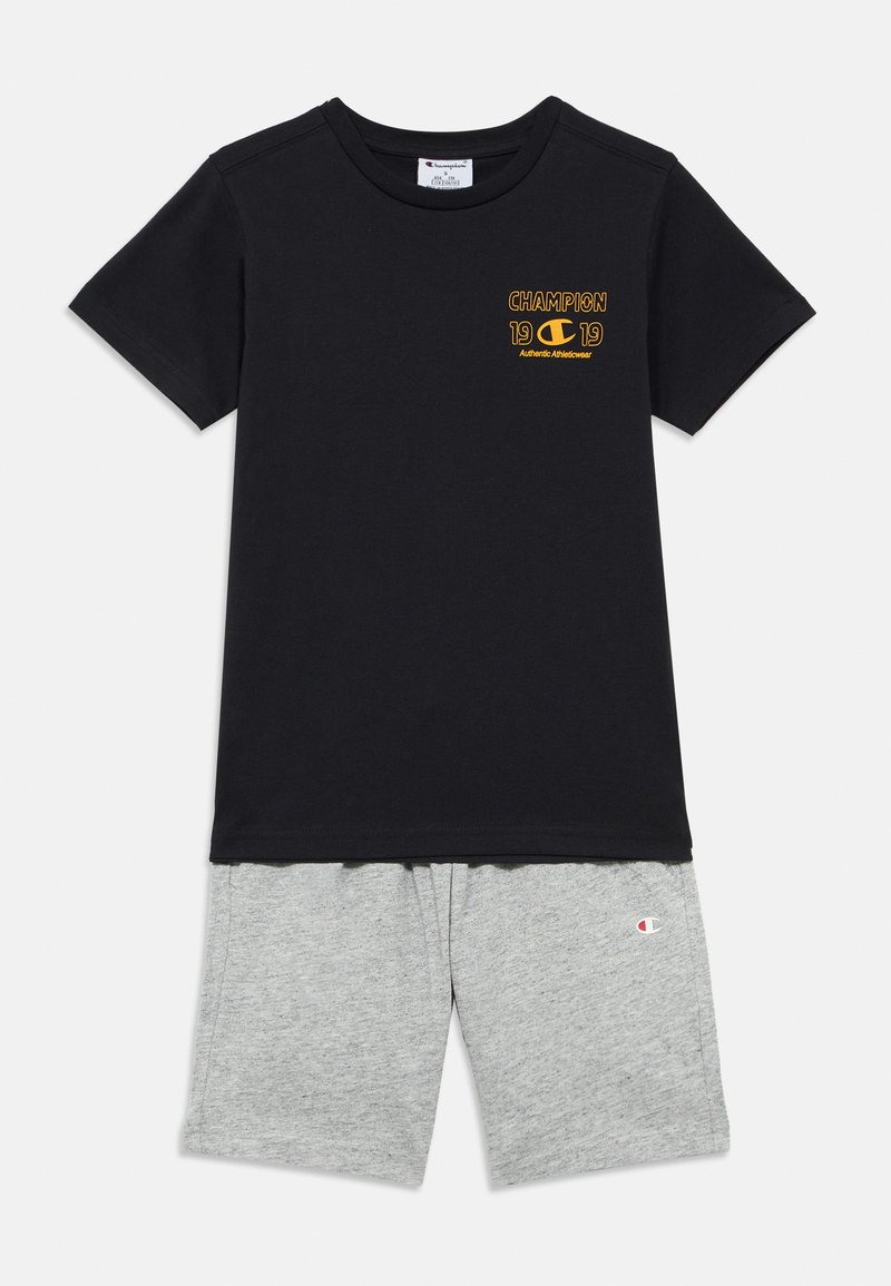Μαύρο βαμβακερό T-shirt με κίτρινο λογότυπο "Champion" και γκρι σορτς από μαλακό ύφασμα. Τα σορτς διαθέτουν μικρό λογότυπο στο αριστερό πόδι.