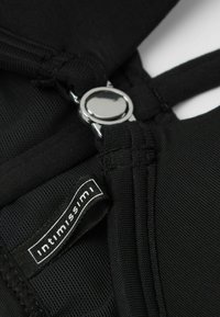 Zwarte lingerie top met verstelbare bandjes, voorzien van een sluiting met zilverkleurige hardware en een label met "intimissimi." Glad textuur, naadloos ontwerp.