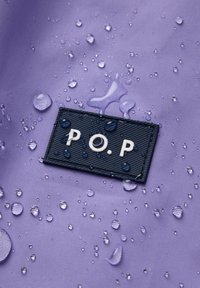 Paarse stof met waterdruppels, met een zwart label waarin de letters "P.O.P." in het wit zijn bedrukt, omringd door een textuurpatroon.