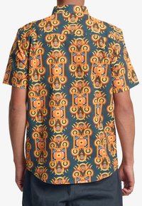 Camicia a maniche corte con un vivace motivo geometrico arancione e giallo su uno sfondo blu scuro. Il materiale appare leggero e con una texture.