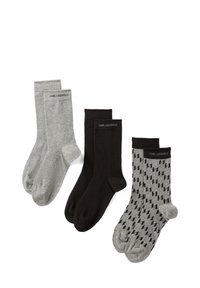 Three pairs of socks: one grey, one black, and one grey with a black geometric pattern. Each pair features a knitted logo.