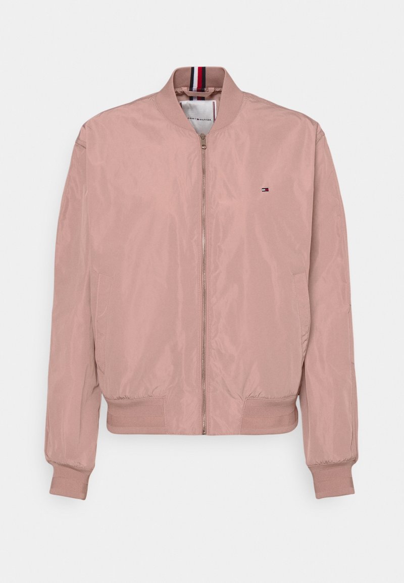 Blouson bomber rose clair avec fermeture éclair à l'avant, col, poignets et bas côteletés, avec un petit logo Tommy Hilfiger sur la poitrine.