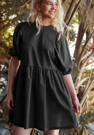 Čierne šaty s puff-sleeve rukávmi, tesne priliehajúcim korzetom a rozšírenou sukňou. Hladký materiál, dĺžka po kolená, so zberaným pásom.