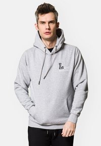 Szary bawełniany hoodie z przednią kieszenią, kapturem ze sznurkiem oraz nadrukowanym logo na lewej piersi. Posiada ściągacze przy mankietach i u dołu.