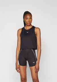 Must musta stiilne lühike sporttop ja kõrge vöökoha lühikesed püksid, millel on kontrastne valge äär. Rinnal ja reiel on väike logo. Sile tekstuur.