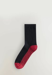 Mustat puuvillasukat, joissa on uritettu pinta, punaisella varpaalla ja koristeellisella punaisella kuviolla sivuilla. Mukavuus keskiössä.