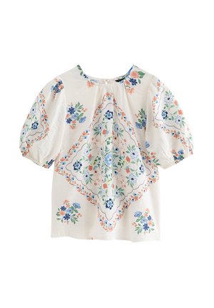 Blusa blanca con mangas abullonadas con motivos florales en azul, verde y melocotón dispuestos en un diamante central y racimos dispersos.