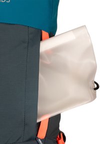 Une poche à eau transparente partiellement insérée dans la poche latérale d'un sac à dos de randonnée bleu et gris avec des sangles orange.