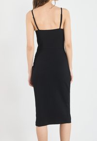 Schwarzes, geripptes Midikleid mit dünnen Trägern, figurbetonendem Schnitt und glatter Textur, das einen geraden Saum und einen hohen Schlitz an der Seite aufweist.