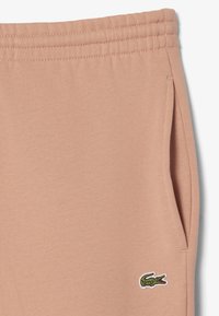 Persikofärgade mjukisbyxor i mjuk bomullsblandning, med resårmidja, sidofickor och en liten broderad krokodil-logotyp.