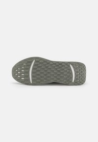 Semelle de chaussure en caoutchouc avec une surface texturée, de couleur grise, comportant des sections à motifs et un léger design en arc pour plus de flexibilité et d'adhérence.