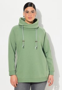 Felpa verde con collo alto a cappuccio, cordini regolabili e tasche laterali. Presenta una texture morbida e un design dal fit rilassato.
