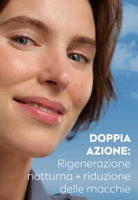 Primo piano di un volto con pelle liscia e chiara e sottili imperfezioni. I capelli sono di un marrone medio, con una consistenza morbida. Lo sfondo è di un blu sfumato.