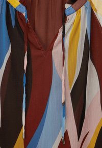 Blusa multicolore con scollo a V, con strisce marroni, blu, gialle e rosa, realizzata in un tessuto testurizzato, accentuata da lacci.