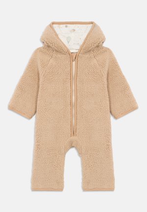 Combinaison en peluche beige pour tout-petits avec capuche, fermeture éclair sur le devant, et doublure intérieure à motifs représentant des montgolfières et des étoiles.