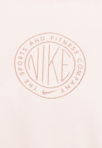 Růžový bavlněný svetr s kulatým výstřihem, s vyraženým kruhovým logem s nápisem "NIKE" a "SPORTOVNÍ A FITNESS SPOLEČNOST" v béžové výšivce.