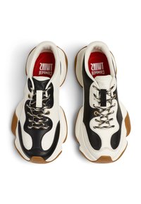 Klobige Sneaker mit einem schwarzen Lederobermaterial und weißen Paneelen. Sie verfügen über goldakzentuierte Schnürsenkel, eine strukturierte Sohle und rote Einlegesohlen.