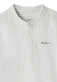 Camicia bianca a righe con colletto alla mandarino, dotata di una pattina con bottoni e un logo ricamato in grigio sul lato sinistro.
