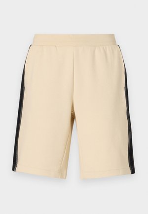 Pantalones cortos beige hechos de una tela suave con paneles laterales de malla negra. Cintura elástica y piernas de corte recto. Textura suave y diseño minimalista.