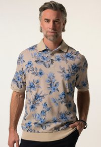 Květinová polo košile s béžovým podkladem a modrými květinovými vzory, krátkými rukávy a kontrastním límcem se třemi knoflíky.